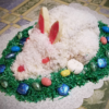Red Velvet Cake covered with Cream Cheese Frosting Coconut, surrounded by Grass Coconut and Easter Candies