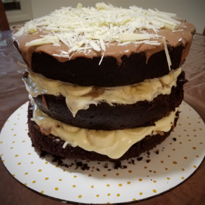 Banana Foster Fudge Cake with cream cheese filling and topped with chocolate ganache and white chocolate curls