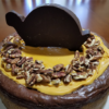 Chocolate Turtle Cheesecake layered with Caramel, Toasted Pecans, Rich Chocolate Filling, and topped with Salted Caramel Sauce and more Pecans