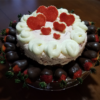 Red Velvet Strawberry Cheesecake topped with White Chocolate hearts and chocolate covered strawberries